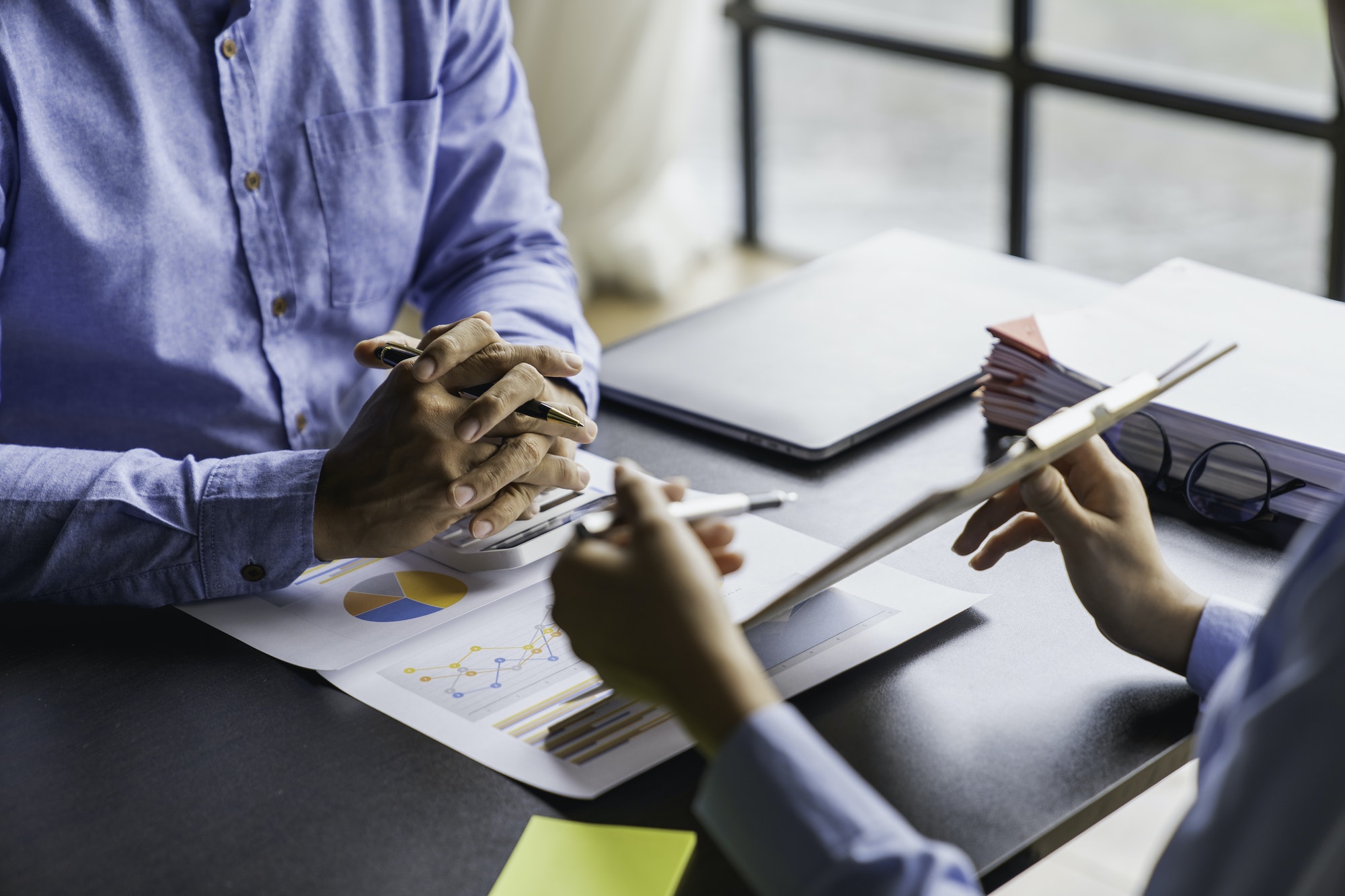 Paperwork and hands on a board room table at a business presentation or seminar. analysis report Che